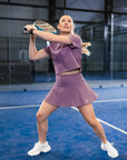 Modell i aktion på padelbanan, klädd i Maya Ribbed Skirt i dusty purple, visar kjolens funktionalitet och stil under spel.