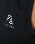 Detaljbild på Cleo Tank – Felize León-logga på svart snabbtorkande tyg