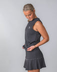 Bild på modell från sidan med Cleo Tank Top – Felize León-logga och snabbtorkande material. Matchande padel/tenniskjol med snygga detaljer runt om kjolen