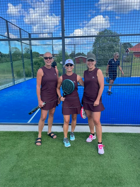 CLEO Performance Tank Top i burgundy utanför padelbanan. Det stilrena och mångsidiga linnet fungerar lika bra för en avslappnad dag i stan som för träning, tack vare dess snygga snitt och färg.