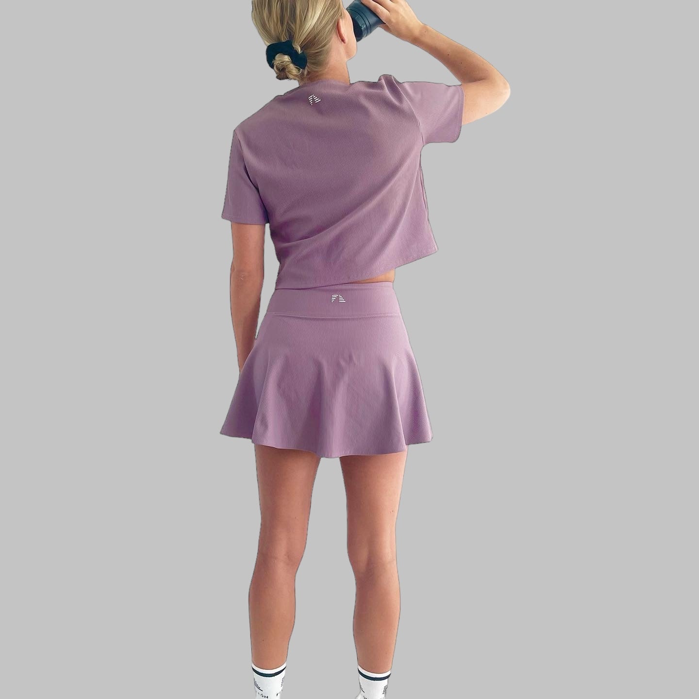 Helkroppsbild bakifrån av modell i ett komplett set med Maya Ribbed Skirt i dusty purple, trendig och sportig look.