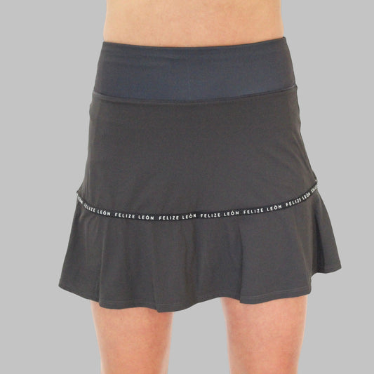 Frontvy av Iza Performance Skirt i graphite grey på modell mot enfärgad bakgrund, visar kjolens klassiska snitt och höga, bekväma midja, idealisk för både padel och tennis.