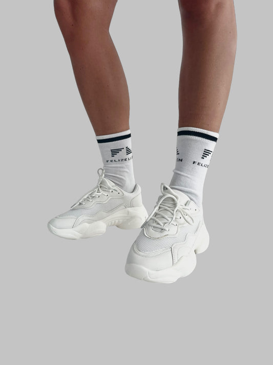 Sportstrumpor, padel och tennis, modell som bär sneakers och strumpor med en enfärgad bakgrund