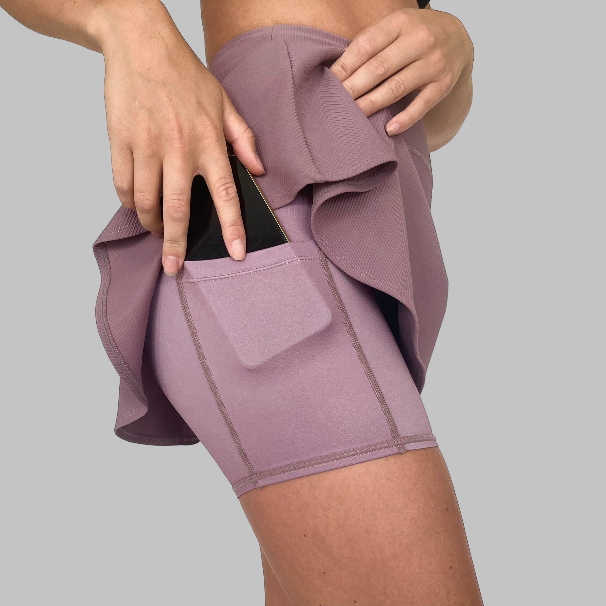 Sidovy av Maya Ribbed Skirt i dusty purple där modellen demonstrerar användningen av mobilfickan.